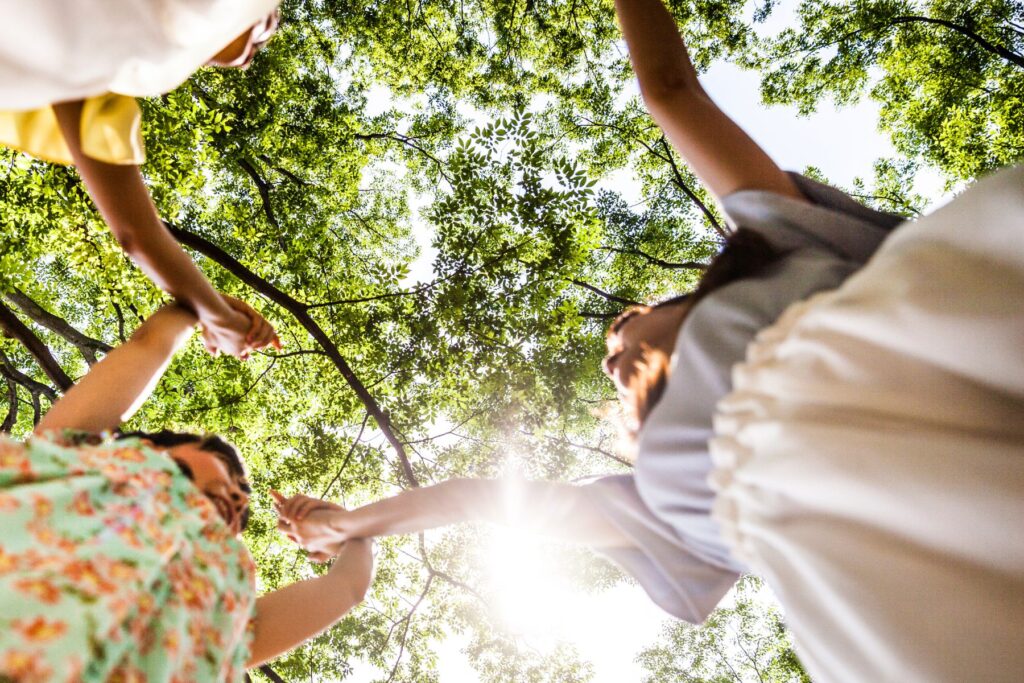 Kinder tanzen im Wald - Aufnahme von unten - man sieht das Blätterdach