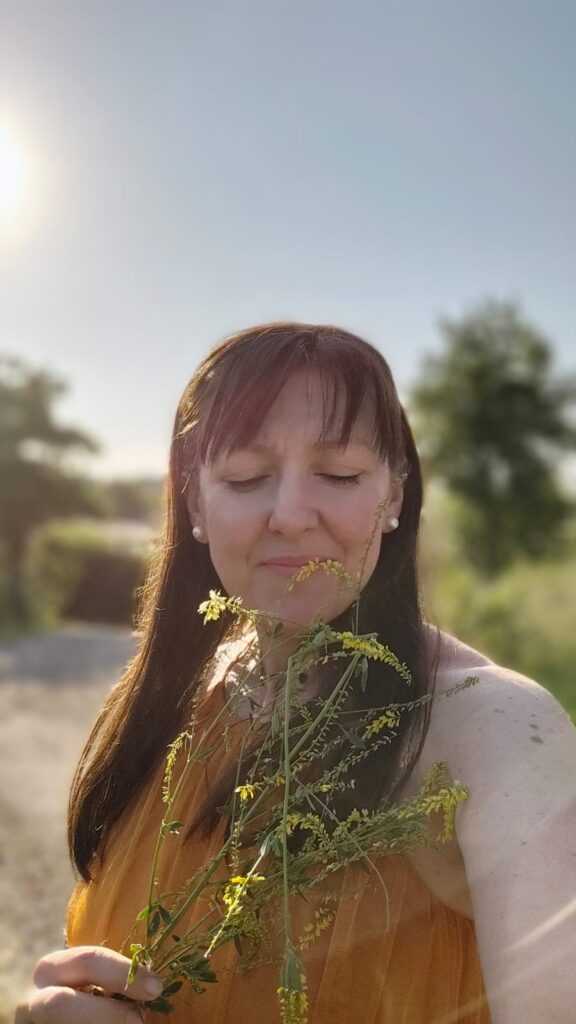 Astrid Marion Hüterin alten Wissens mit geschlossenen Augen und Kräutern bei Sonnenuntergang - Naturseminare Naturhof Schranz Burgenland